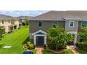 Charming two-story townhome featuring a blue front door, lush green lawn, and brick walkway at 130 Claire Ln, Davenport, FL 33837