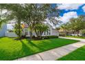 Landscaped front yard featuring lush green grass and mature trees surrounding a gray home at 1415 Ellis Fallon Loop, Oviedo, FL 32765