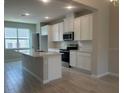 Modern kitchen featuring white cabinets, a large island with a sink, and stainless steel appliances at 15316 Burgtheater Dr, Winter Garden, FL 34787