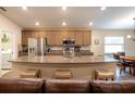 Open kitchen with granite countertops, stainless steel appliances, and a breakfast bar overlooking the living area at 5416 Tessin Trl, St Cloud, FL 34771