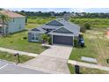 Aerial view showcases a well-maintained gray single-story home with a two-car garage and green surroundings at 7744 Country Run Pkwy, Orlando, FL 32818