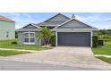 Single-story home features a gray exterior, a well-maintained lawn, and a two-car garage at 7744 Country Run Pkwy, Orlando, FL 32818