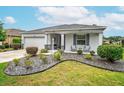 Well-maintained home with a stone-mulched garden, green lawn, and welcoming front porch with seating at 8336 Sw 77Th Ct, Ocala, FL 34476