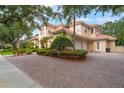 A Mediterranean-style home with manicured landscaping, red tile roof, and brick paved driveway at 8814 Southern Breeze Dr, Orlando, FL 32836