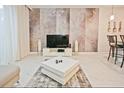 Modern living room with accent wall, entertainment center, and neutral-toned furniture at 9061 Dogleg Dr, Davenport, FL 33896