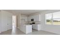 Open-concept kitchen featuring white cabinets, stainless steel appliances, island with sink, and tile floors at 9113 Wildlight, Wildwood, FL 34785