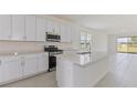 Modern kitchen featuring white cabinets, stainless steel appliances, large island, and tile flooring at 9113 Wildlight, Wildwood, FL 34785