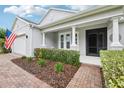 Inviting front porch with lush landscaping, a brick walkway, and a classic American flag at 106 Mist Flower Ln, Groveland, FL 34736