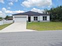 Single-story home featuring white siding, black trim, a dark roof, and a two-car garage at 2699 Sw 161St Loop, Ocala, FL 34473