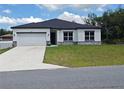 Single-story home featuring white siding, black trim, a dark roof, and a two-car garage at 2699 Sw 161St Loop, Ocala, FL 34473