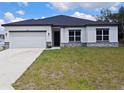 Charming single-story home with a white exterior, dark roof, and an attached two-car garage at 2699 Sw 161St Loop, Ocala, FL 34473