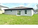 Spacious backyard with lush green grass and a sliding glass door leading inside at 319 Anchovie Ct, Poinciana, FL 34759