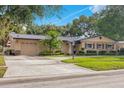 Well-maintained home featuring an attached garage, long driveway, and lush, green landscaping at 3405 Werber St, Orlando, FL 32806