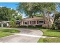 Charming home with mature trees and a circular driveway surrounded by a green lawn at 3405 Werber St, Orlando, FL 32806