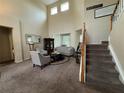Open-concept living room featuring tall ceilings, carpet flooring, stairs, and ample natural light at 6224 Zane Dr, Mount Dora, FL 32757