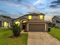 Charming two-story home featuring an attached two-car garage and well-manicured lawn and landscaped yard at dusk at 13404 Bradwater Ct, Orlando, FL 32828