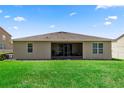 A view of the back of the home and lawn showing the screened lanai and simple landscaping at 1431 Leitrim Loop, Apopka, FL 32703