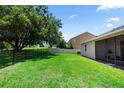 Large, grassy, fenced backyard with partial view of a home screened lanai at 1431 Leitrim Loop, Apopka, FL 32703