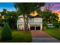 Charming two-story home features a manicured lawn, brick driveway, and inviting front porch with second-story balcony at 2607 Lafayette Ave, Winter Park, FL 32789