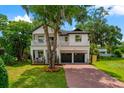 Charming two-story home features a manicured lawn, brick driveway, and inviting front porch with second-story balcony at 2607 Lafayette Ave, Winter Park, FL 32789