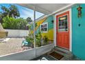 View of a colorful exterior porch with a bright orange door and a screen enclosure at 318 Palm St, New Smyrna Beach, FL 32168
