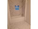 Newly renovated bathroom features marble tile and a sleek bathtub at 4 N Christiana Ave, Apopka, FL 32703