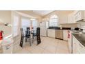 Bright kitchen featuring white cabinets, stainless steel appliances, and a glass-top dining table at 4700 Prairie Point Blvd, Kissimmee, FL 34746