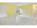 Bright living room featuring yellow walls, white tile floors, and multiple windows for natural light at 7609 Winter Shade Dr, Orlando, FL 32822