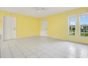 Bright living room featuring yellow walls, white tile floors, and multiple windows for natural light at 7609 Winter Shade Dr, Orlando, FL 32822