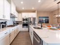 Modern kitchen with white cabinets, quartz countertops, stainless steel appliances, and an open layout to the dining area at 7951 Haverhill Way, Kissimmee, FL 34747