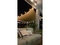 Inviting outdoor seating area under a shade sail and string lights, offering a relaxing space with plush pillows at 9422 Jaywood Rd, Winter Garden, FL 34787
