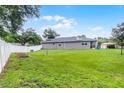 Well-maintained back yard with a white fence, green lawn, and solar panels on the home's roof at 1020 Taproot Dr, Winter Springs, FL 32708