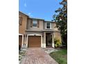 Townhome showcasing a one car garage, brick paved driveway, and well-manicured lawn at 11187 Savannah Landing Cir, Orlando, FL 32832