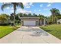 Inviting home with a lush green lawn, mature landscaping, and an expansive driveway at 1907 Sir Lancelot Cir, St Cloud, FL 34772