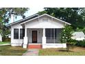 Traditional white home featuring a screened-in porch, brick steps and mature landscaping at 206 N Highland Ave, Winter Garden, FL 34787