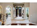 Stunning home foyer with stone floors, arched doorways and impressive double doors, offering a glimpse of the dining area at 2357 Alaqua Dr, Longwood, FL 32779