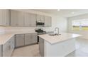 Modern kitchen with grey cabinets, island, stainless steel appliances, and lots of natural light at 3088 Windswept, Wildwood, FL 34785