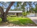 Single-story home featuring a well-maintained lawn, mature trees, a two car garage, and a welcoming front entrance at 310 E Gulley Ave, Oakland, FL 34760