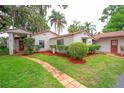 Charming single-story home featuring a red tile roof, lush landscaping, and a brick pathway leading to the front door at 4420 Conway Gardens Rd, Orlando, FL 32806
