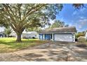 View of the house with blue exterior, white trim and a large tree in the front yard at 7504 Willow Wisp E Dr, Lakeland, FL 33810