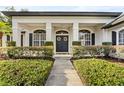 A charming entry to this home is flanked by manicured shrubs and black shutters at 1141 Waldorf Ct, Winter Springs, FL 32708