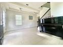 Bright and airy living room with staircase, grand piano, white tile flooring, and large windows at 16611 Toccoa Row, Winter Garden, FL 34787