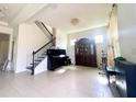 Spacious living room with tile floors, chandelier, and staircase featuring iron balusters and a grand piano at 16611 Toccoa Row, Winter Garden, FL 34787