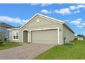 Single-story home with brick driveway, two-car garage, and landscaped front yard for a warm welcome at 189 Luxmore Rd, Groveland, FL 34736