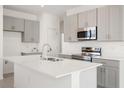 Modern kitchen featuring gray cabinets, stainless steel appliances, and a large center island at 192 Duckweed Ave, Fruitland Park, FL 34731