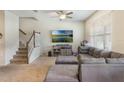 Comfortable living room featuring a large sectional sofa, ceiling fan, and a staircase to the upper level at 2696 Giardino Loop, Kissimmee, FL 34741