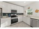 Bright kitchen with stainless steel appliances, modern white cabinets, and decorative tile backsplash at 3941 Willowbrook Dr, Edgewater, FL 32141