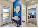 Stylish entryway with a blue accent wall, modern console table, and a view of bedroom and bathroom at 424 Ocean Course Ave, Davenport, FL 33896