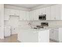 Bright kitchen features white cabinetry, stainless steel appliances and a center island with a sink at 797 Lemon Ave, Fruitland Park, FL 34731