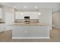 Kitchen island with granite countertops, stainless steel appliances, pendant lighting, and white cabinetry at 928 Pearlwood Loop, Eagle Lake, FL 33839